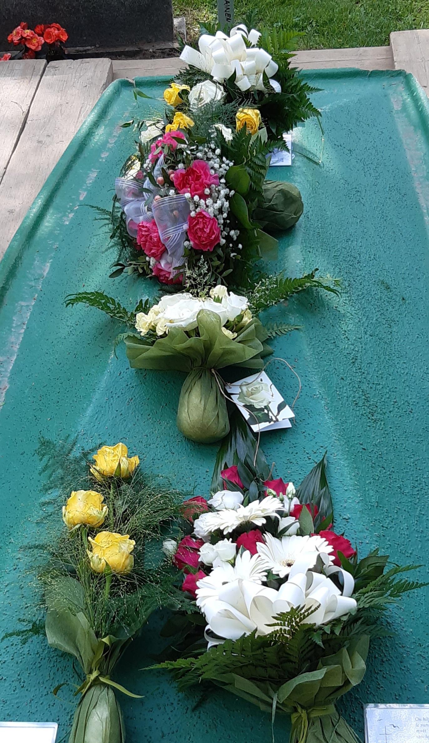 kuvassa hauta, joka peitetty kannella, jonka päällä kukkakimppuja