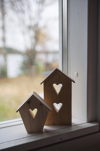 Kaksi talonmuotoista koristetta ikkunalaudalla, joissa sydän sisällä.